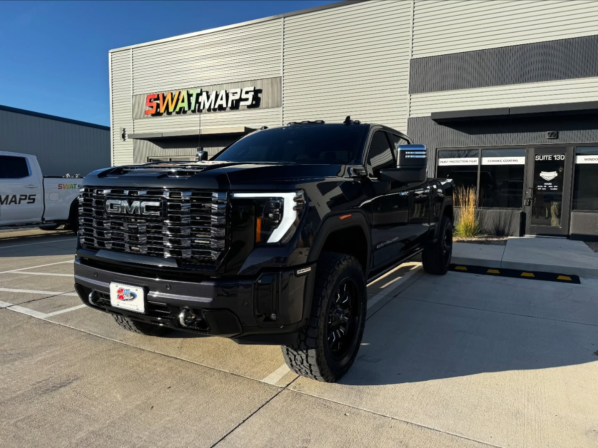 Black GMC Sierra 2500 Denali HD with off-road tires parked in front of SWAT MAPS auto detailing shop