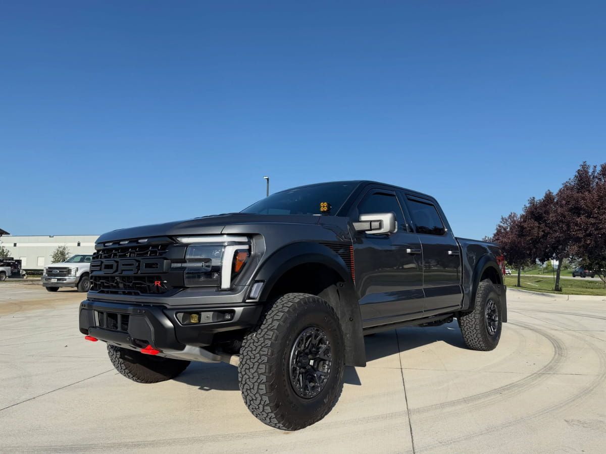 Dark Ford F-150 Raptor pickup truck parked outdoors on a sunny day