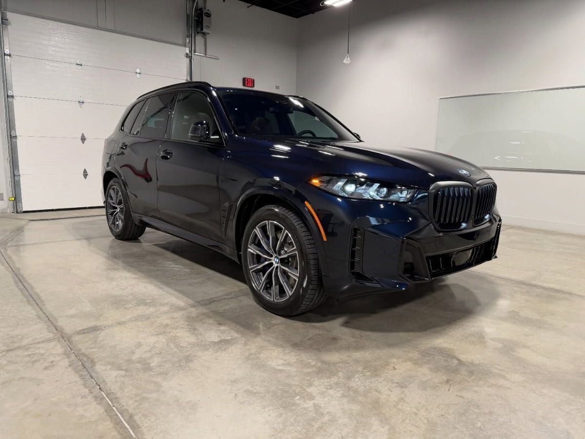Dark blue BMW SUV parked indoors at an auto detailing facility.