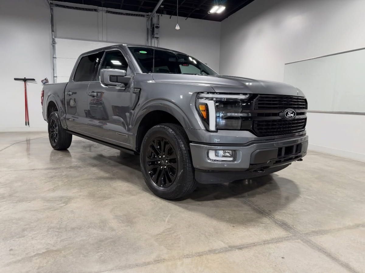 Gray Ford pickup truck with black wheels parked inside an auto detailing workshop.