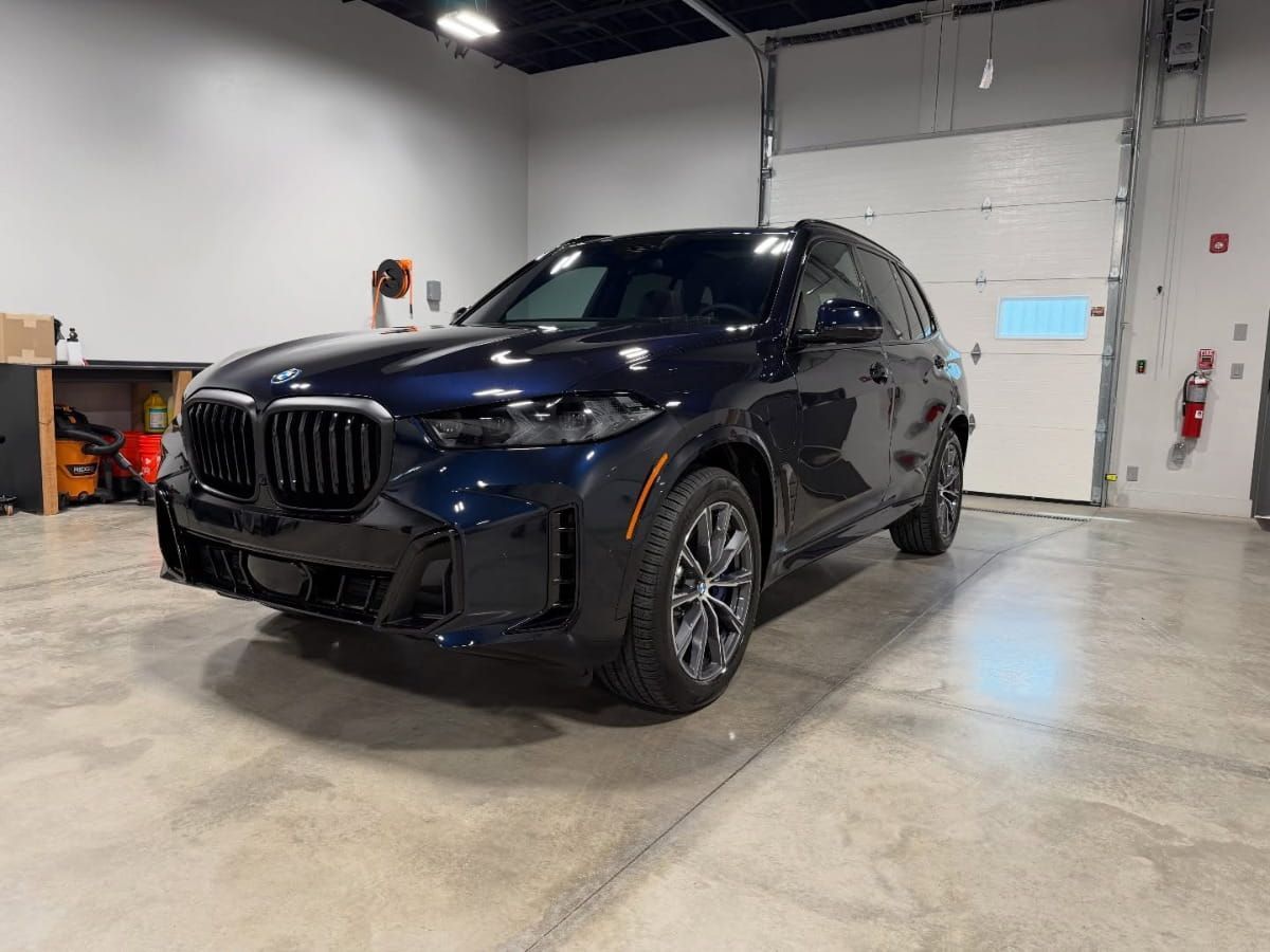 Dark blue BMW X5 with a glossy finish inside the detailing facility.