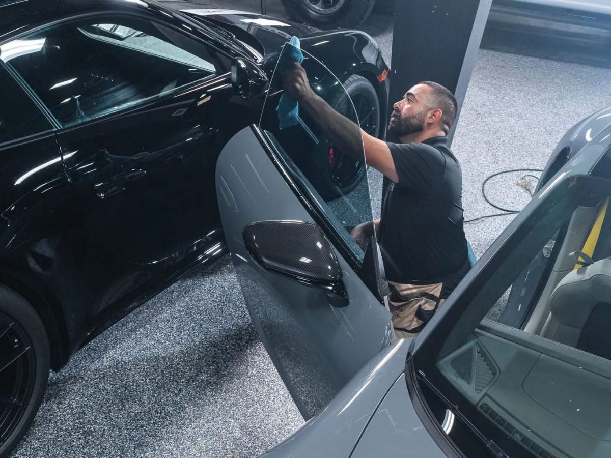 Technician working on automotive window tint inside the DC Auto Pros detailing shop.