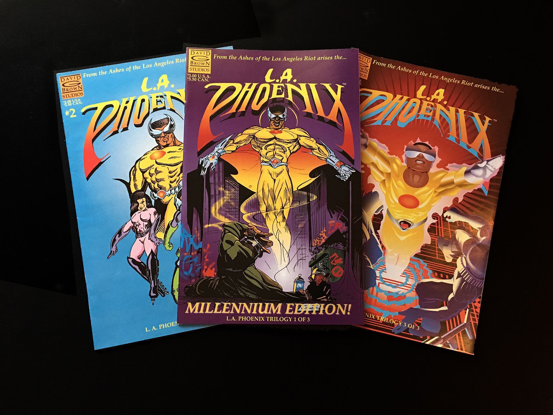 Three L.A. Phoenix comic books: blue, purple, and orange covers with a superhero figure.