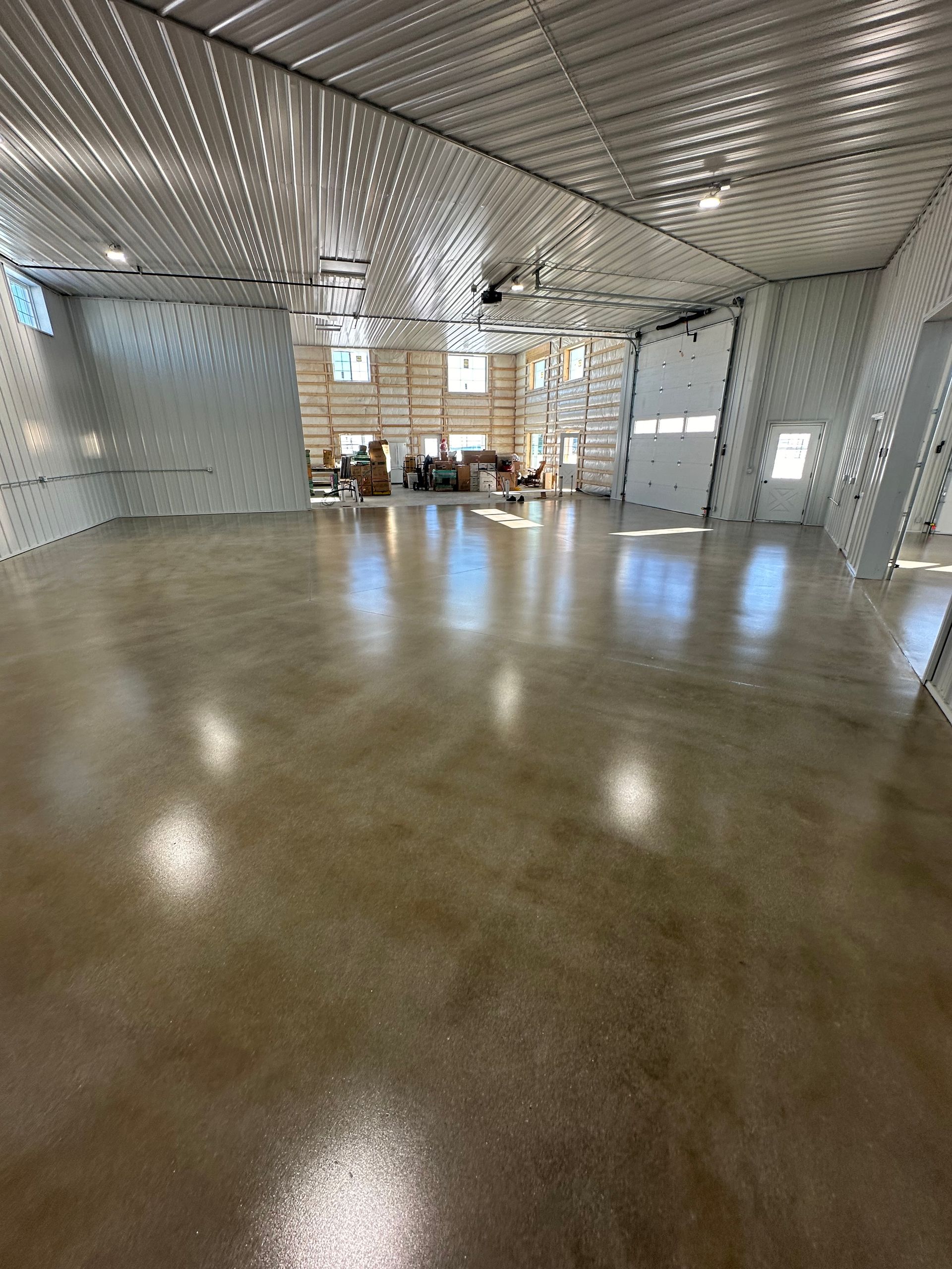 Empty polished hall with reflective ceiling panels and a row of windows at the far end