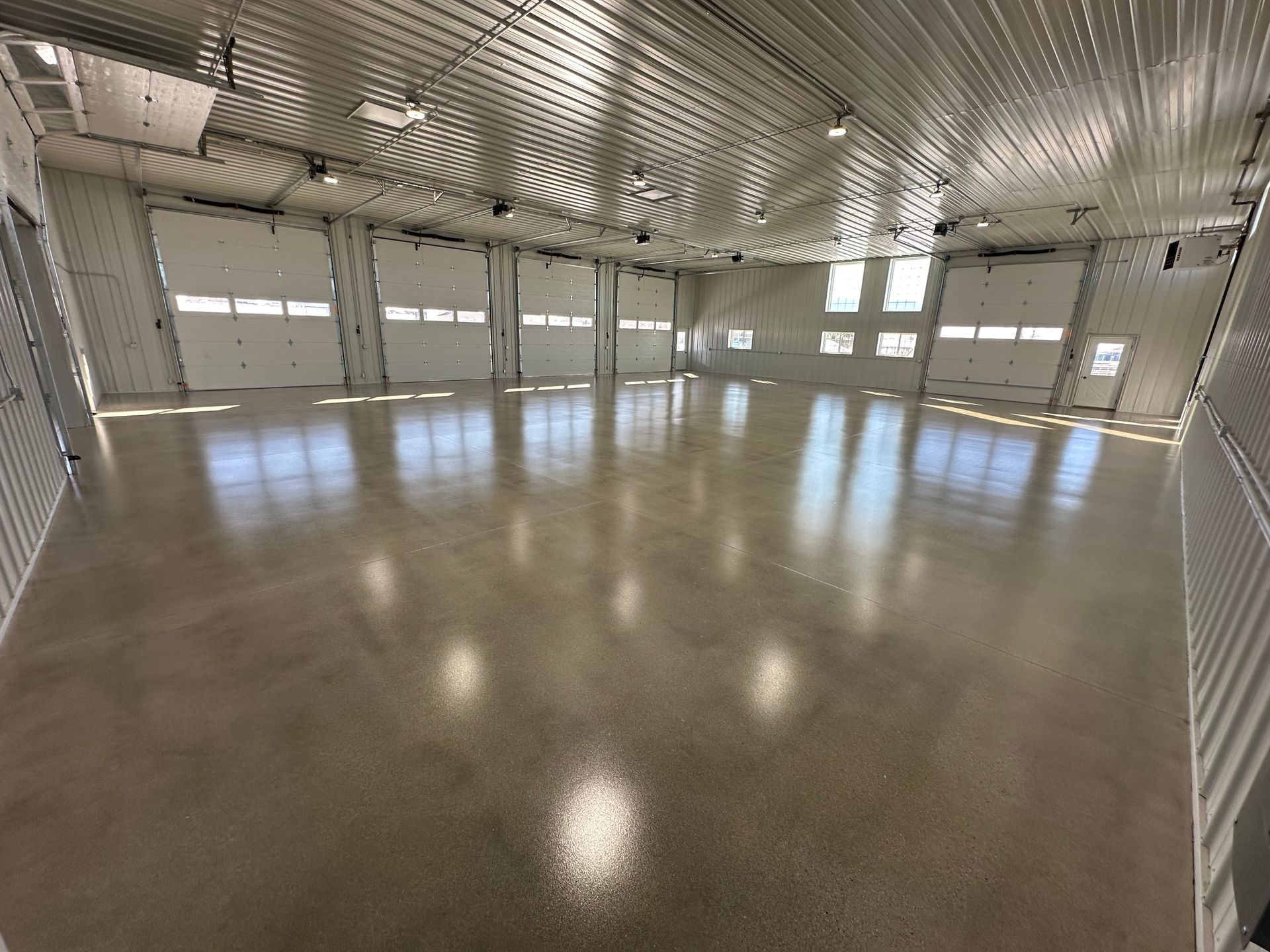 Empty modern hall with polished floor, curved metal ceiling, and large windows letting in daylight