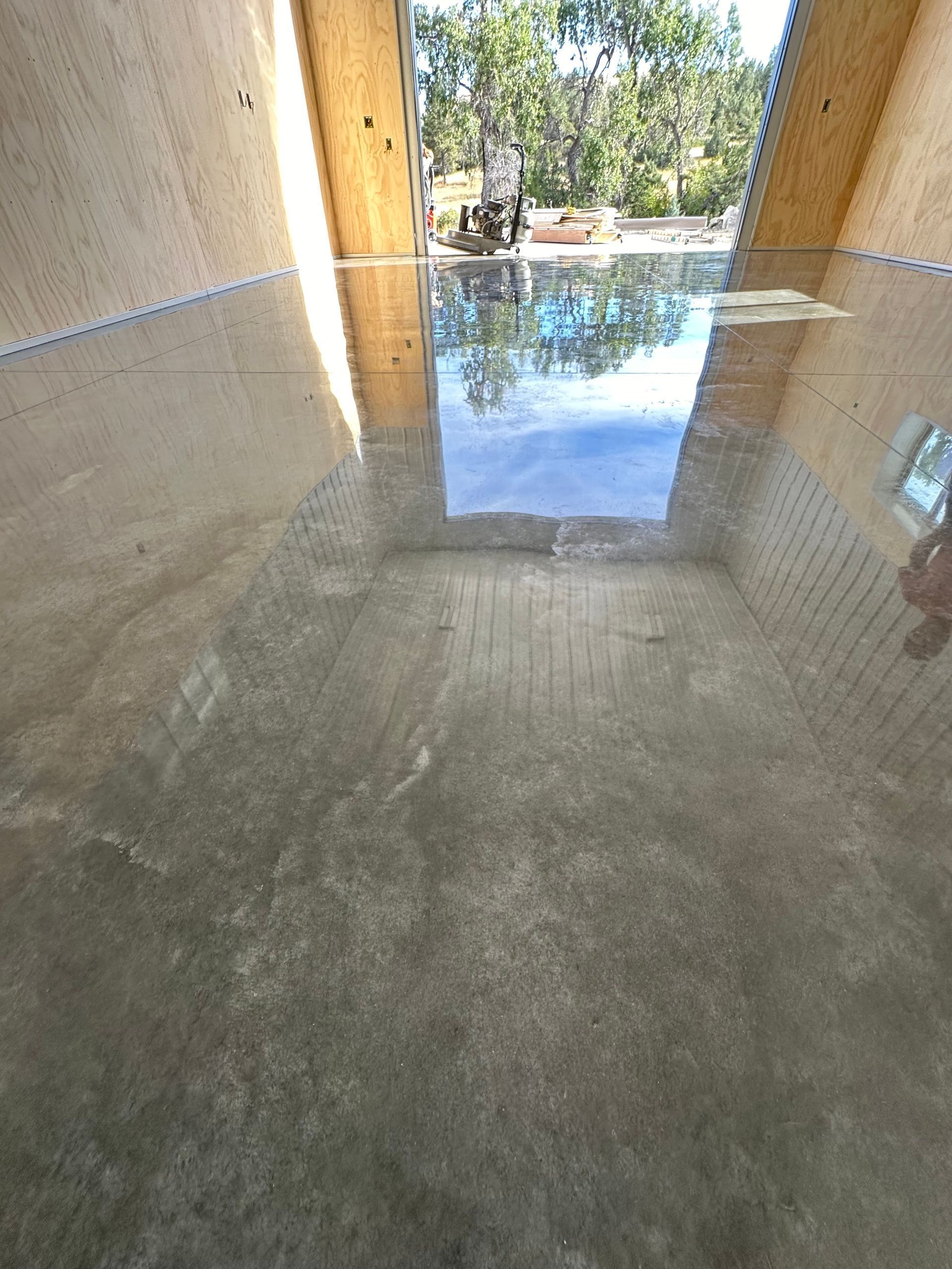 Water-filled concrete tunnel with an open end reflecting trees and sky outside