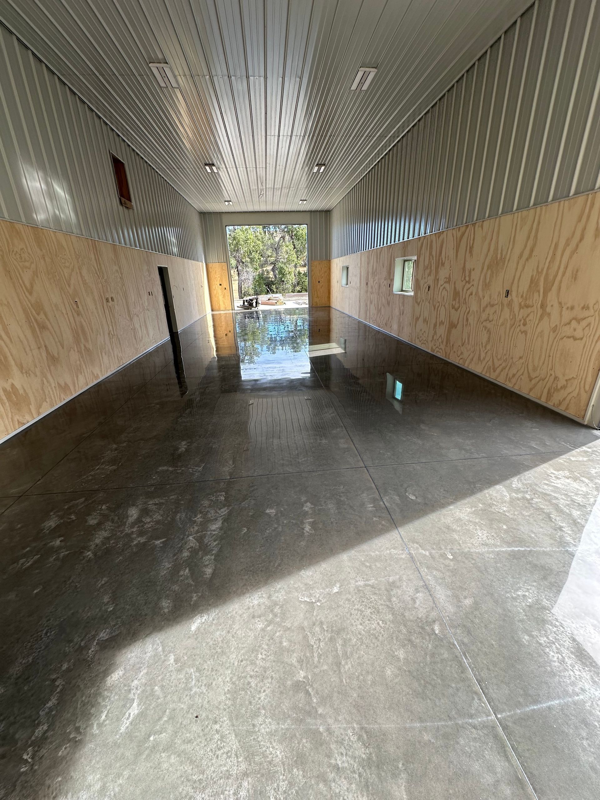 Narrow, tiled corridor with wet floor, sunlight at the far end, and patterned walls and ceiling.