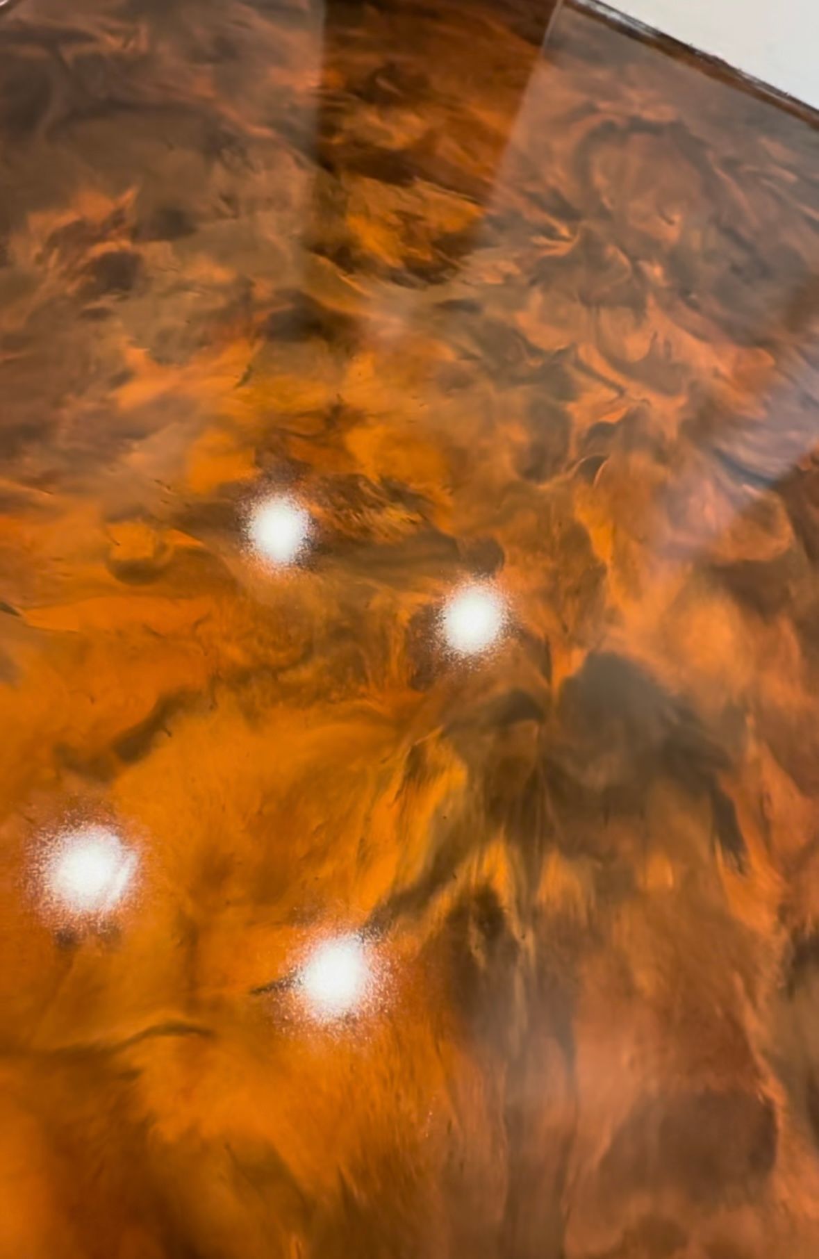 Orange-brown abstract surface with three bright white reflections, glossy and textured