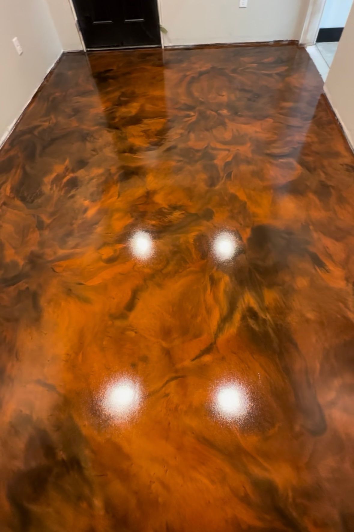 Glossy marbled epoxy floor in orange, brown, and black tones inside a hallway