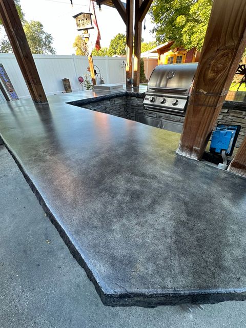 Covered outdoor patio with a wet concrete floor and a built-in grill