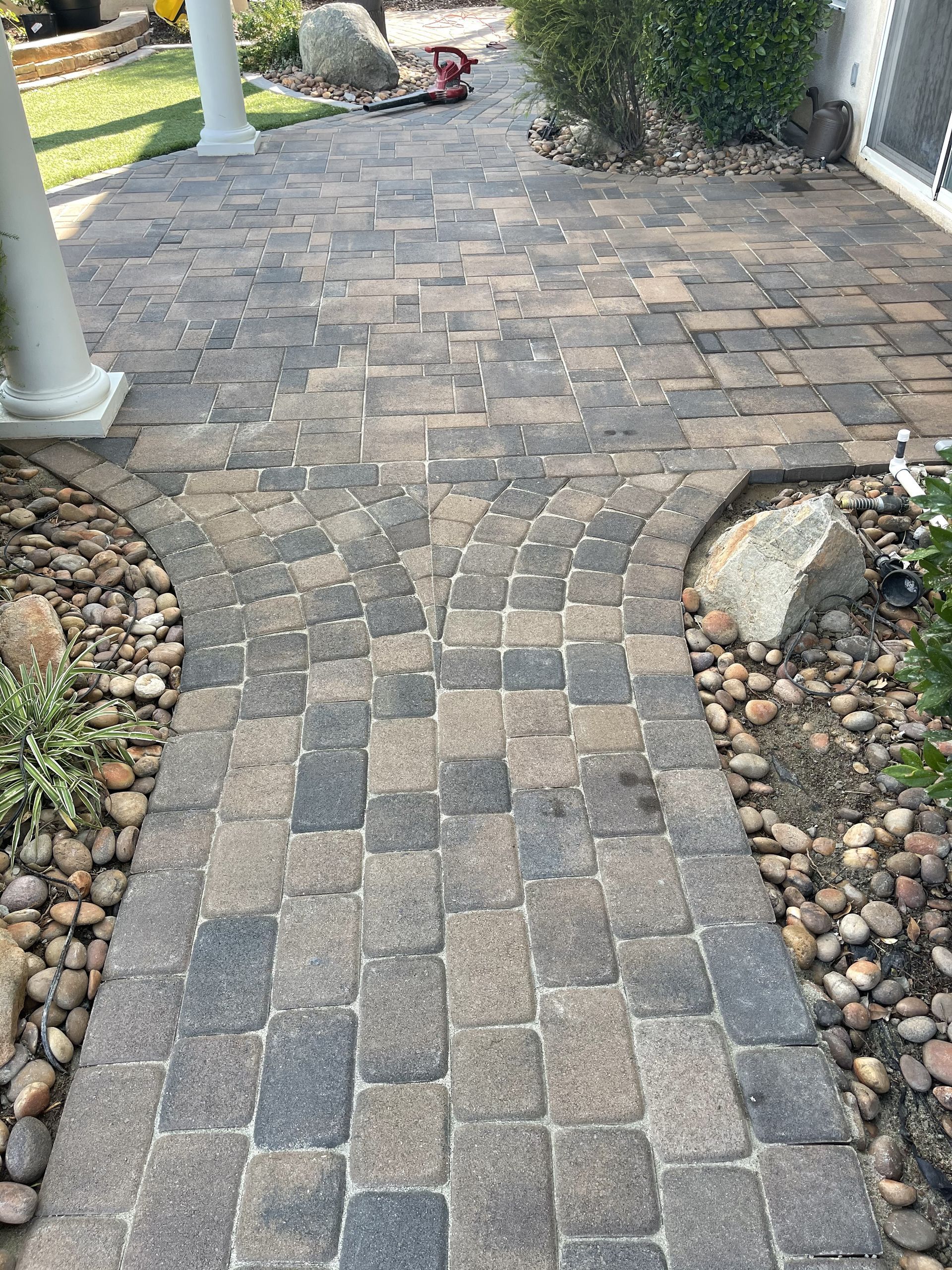 A walkway made of bricks and rocks leading to a house.