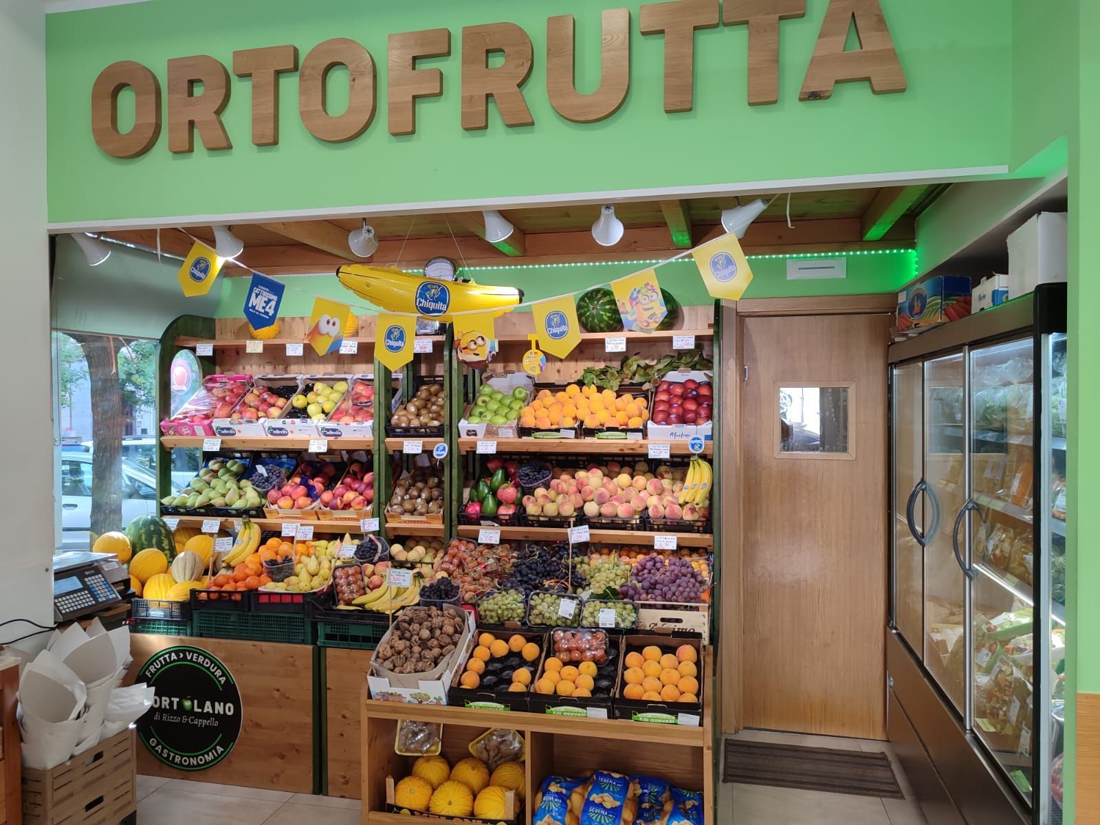 Negozio di frutta e verdura con prodotti esposti sotto l'insegna