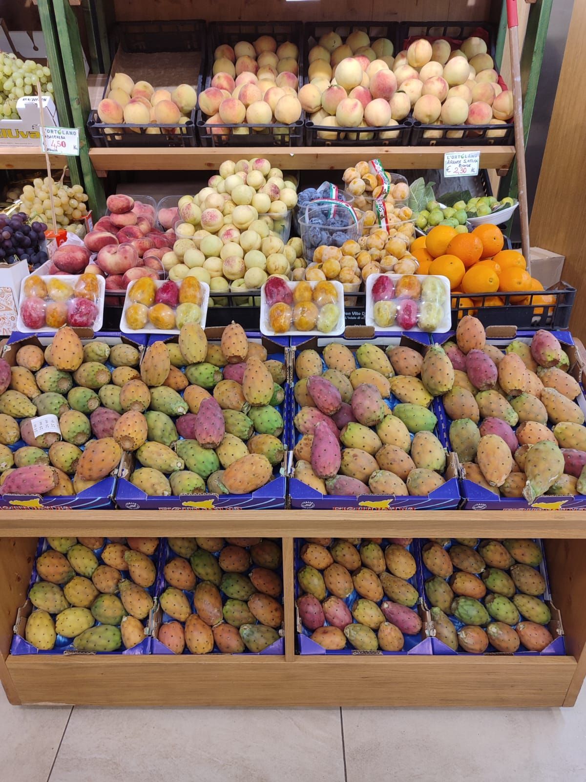 Banco di frutta con fichi d'india, pesche, albicocche e arance.