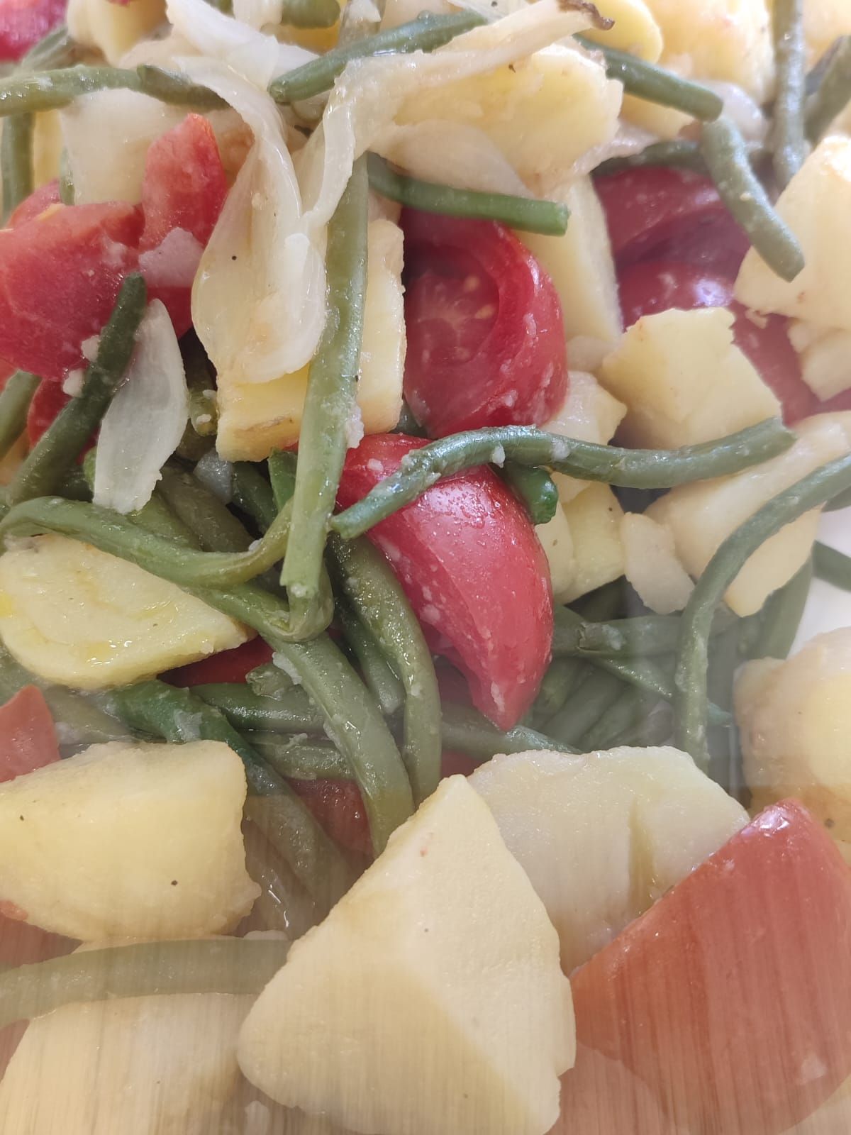Insalata con fagiolini, patate, pomodori e cipolla, in primo piano.