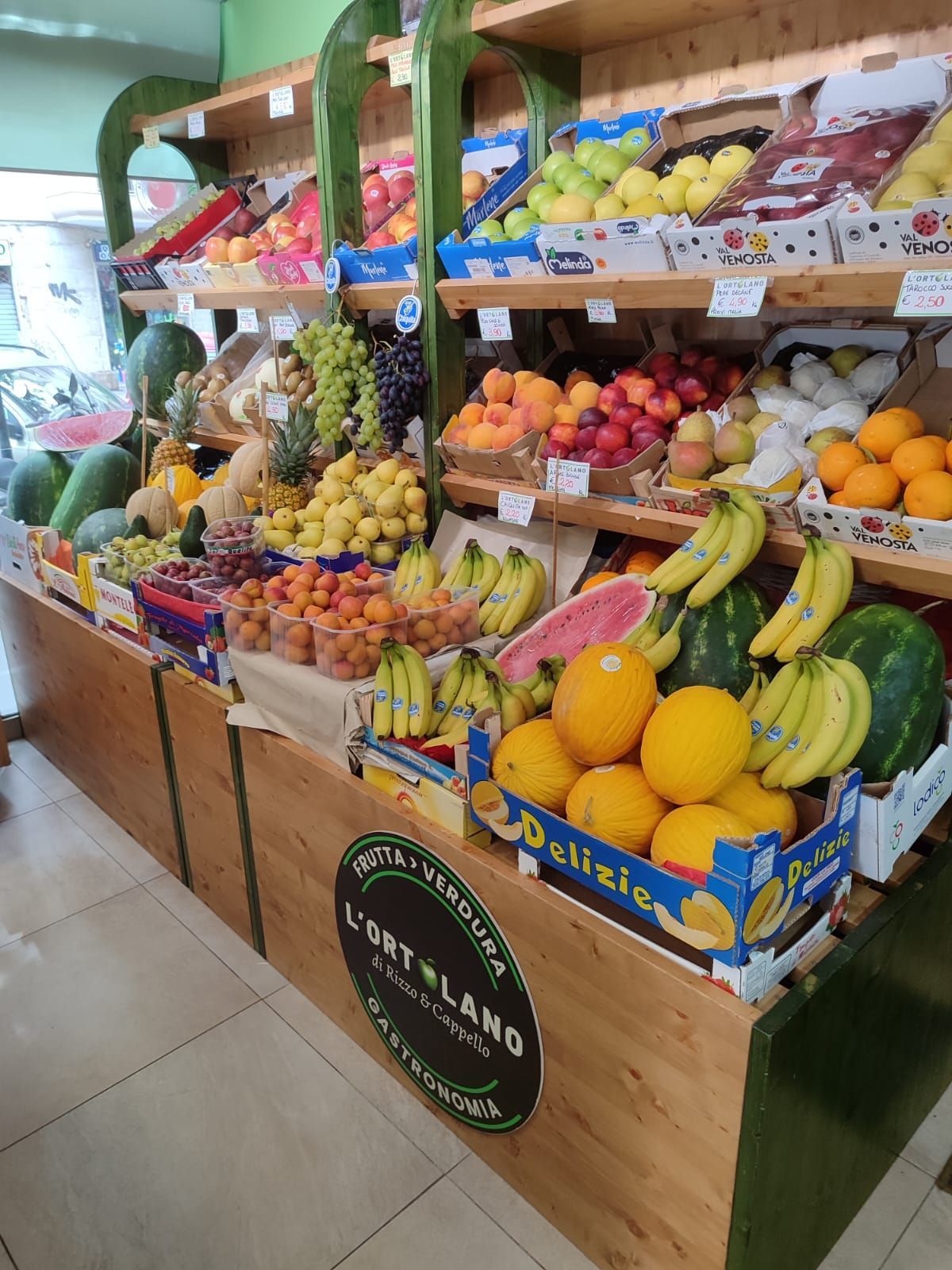 Banco di frutta in legno rifornito di vari tipi di frutta colorata.