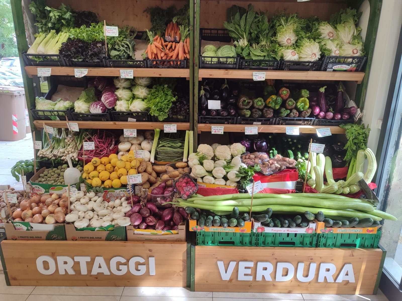Esposizione di prodotti ortofrutticoli con varietà di verdure; scaffali etichettati