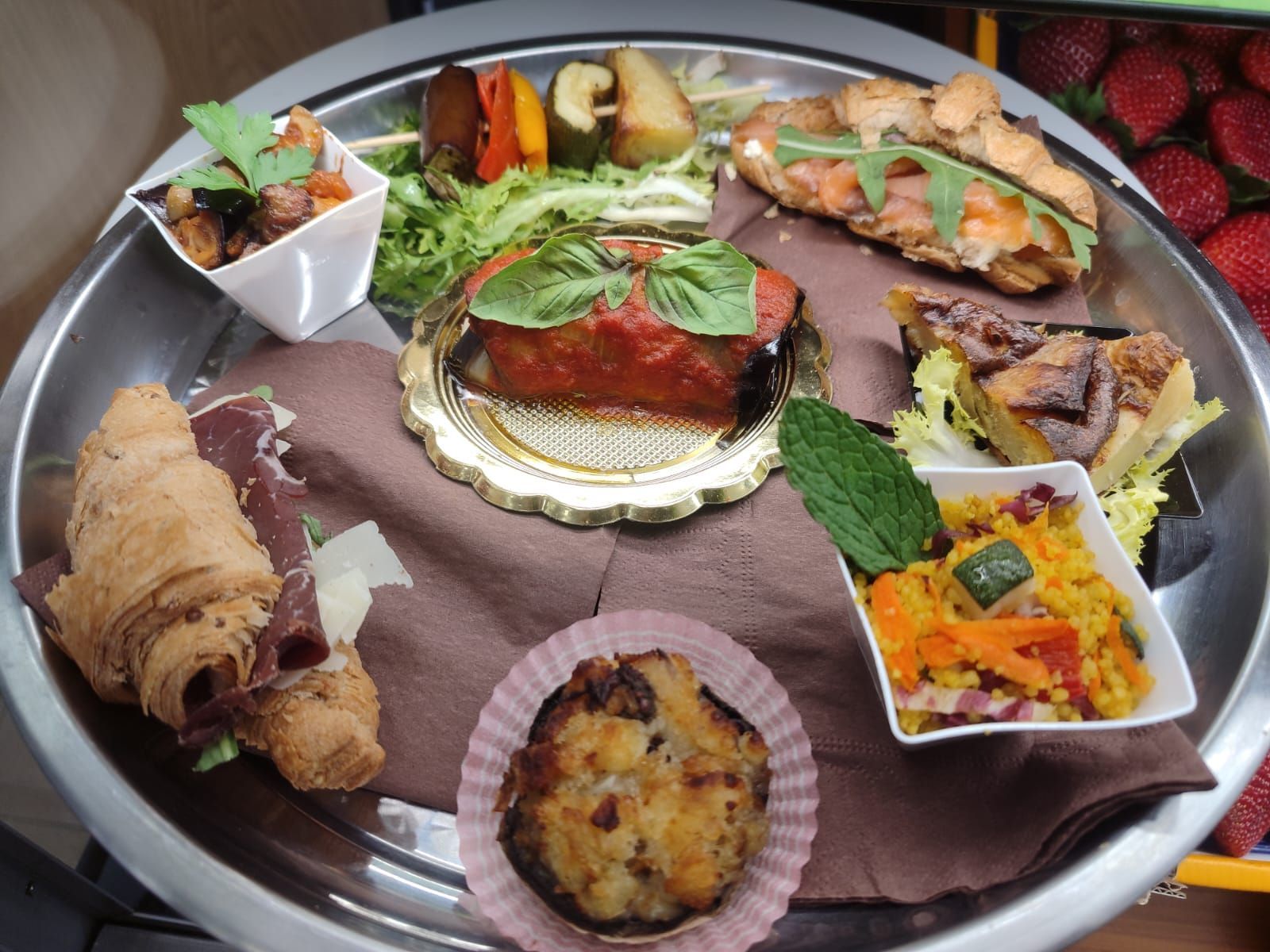 Un piatto di vari antipasti: croissant, pasticcini, verdure e un panino.