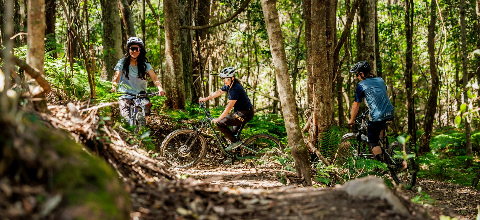 Mountain biker airborne over rocky terrain in a forest.
