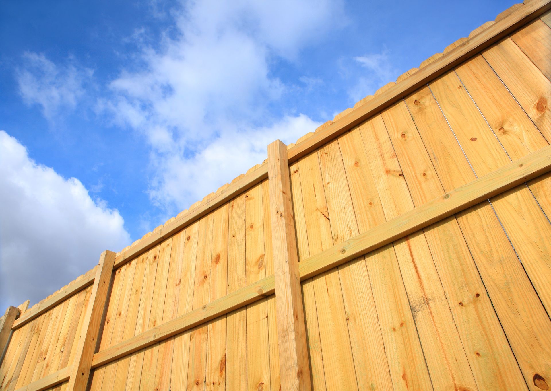 Wooden fence against a cloudy sky showcasing work by a trusted fence installation contractor.