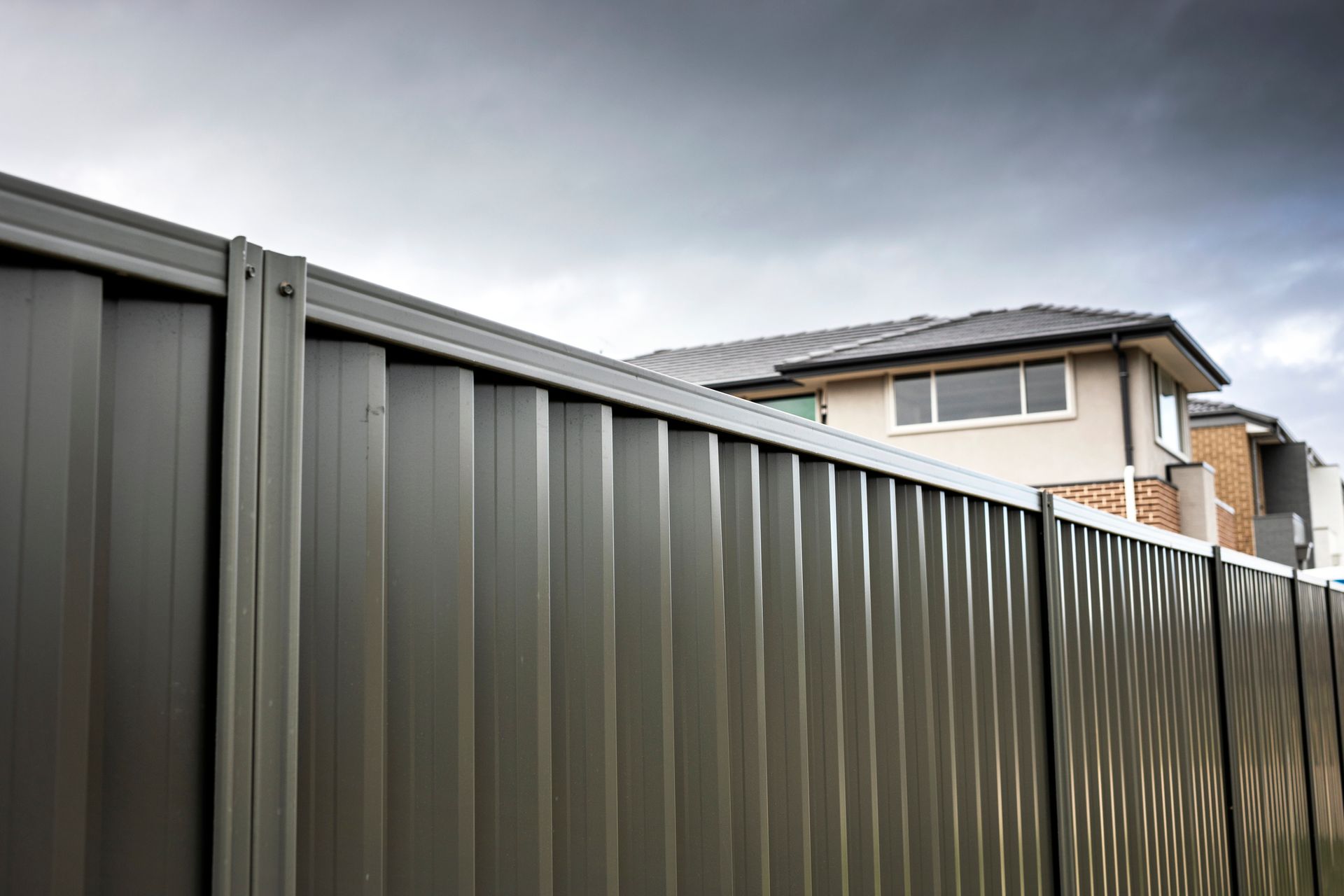 A close up of a metal fence with a house in the background.