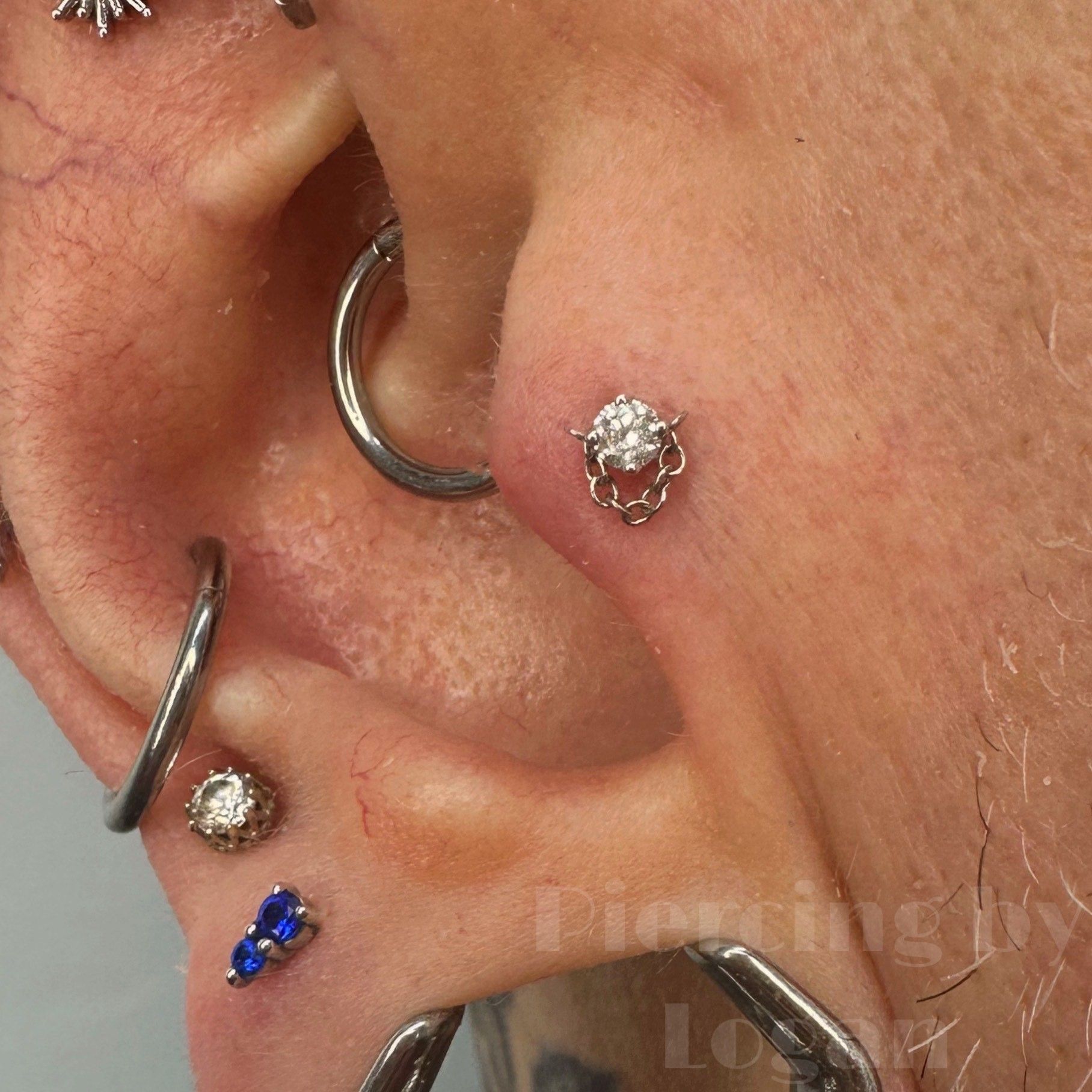 Close-up of ear with multiple piercings, including a stud and rings.