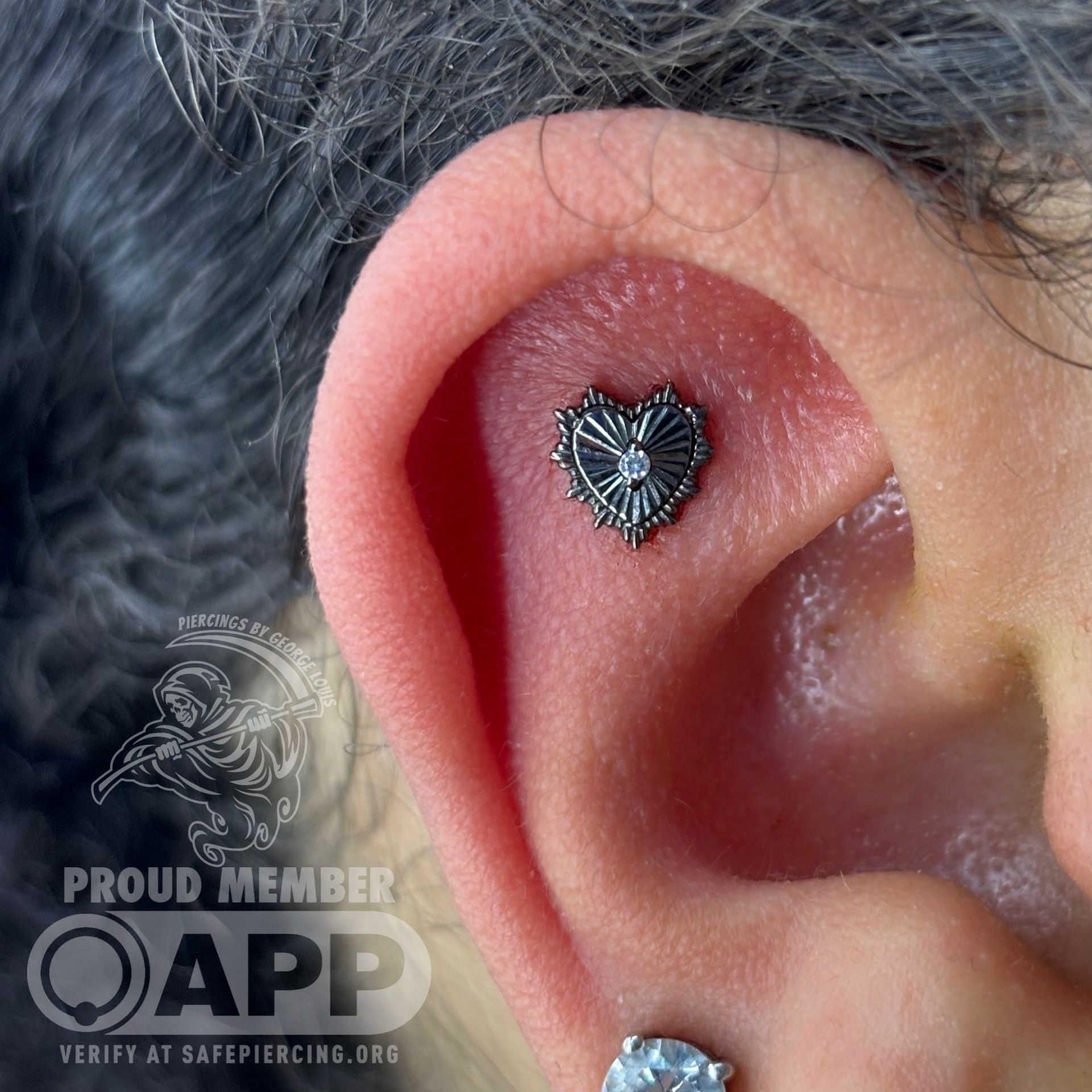 Close-up of a person's ear with a heart-shaped helix piercing with a diamond center.