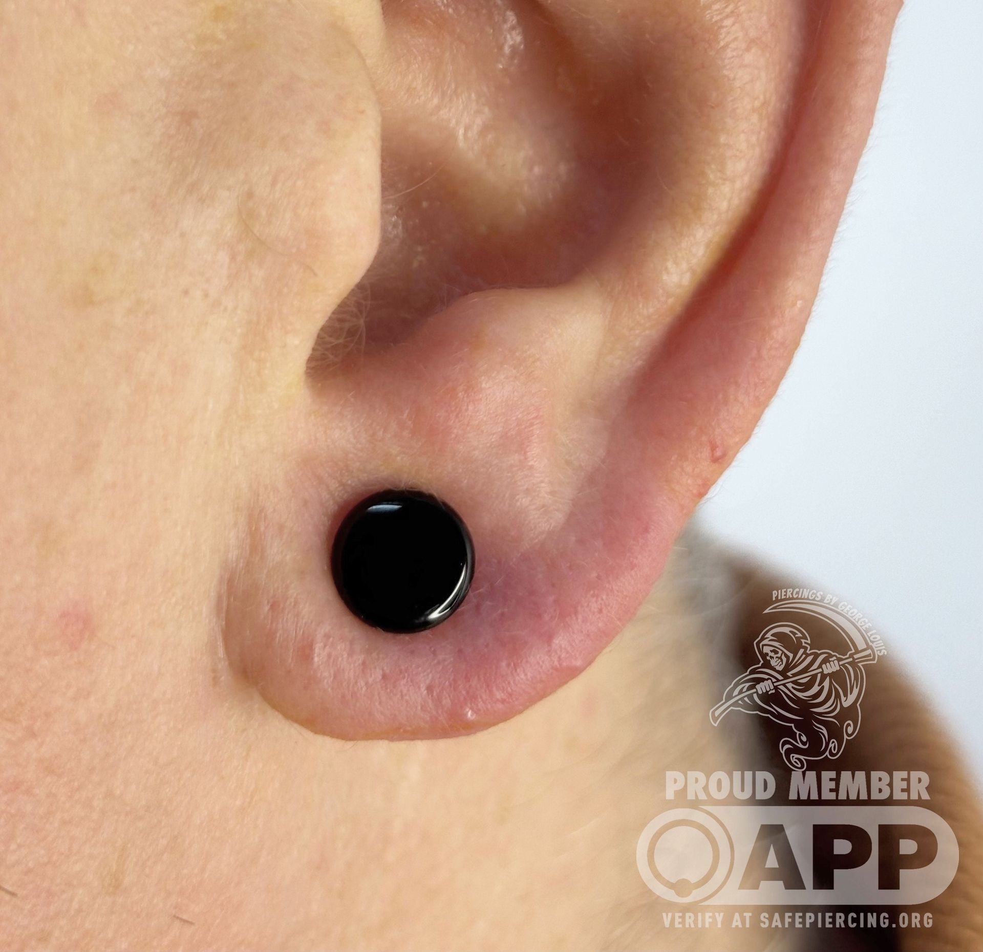 Close-up of an ear with a black plug. The earlobe is pierced and stretched.