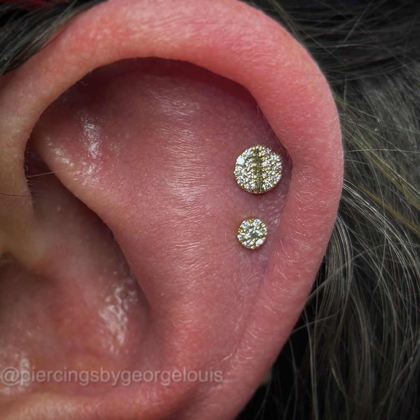 Ear with two gold and diamond piercings.