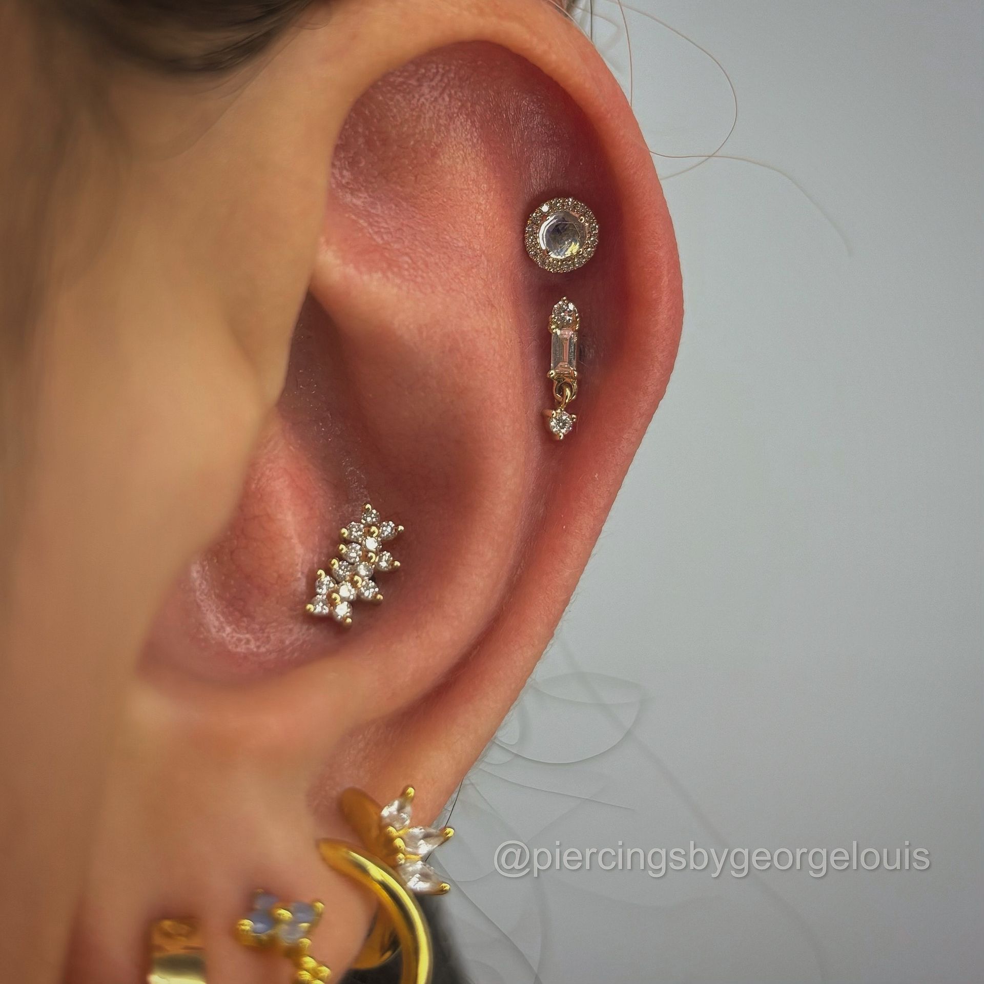 Close-up of ear with multiple gold piercings.
