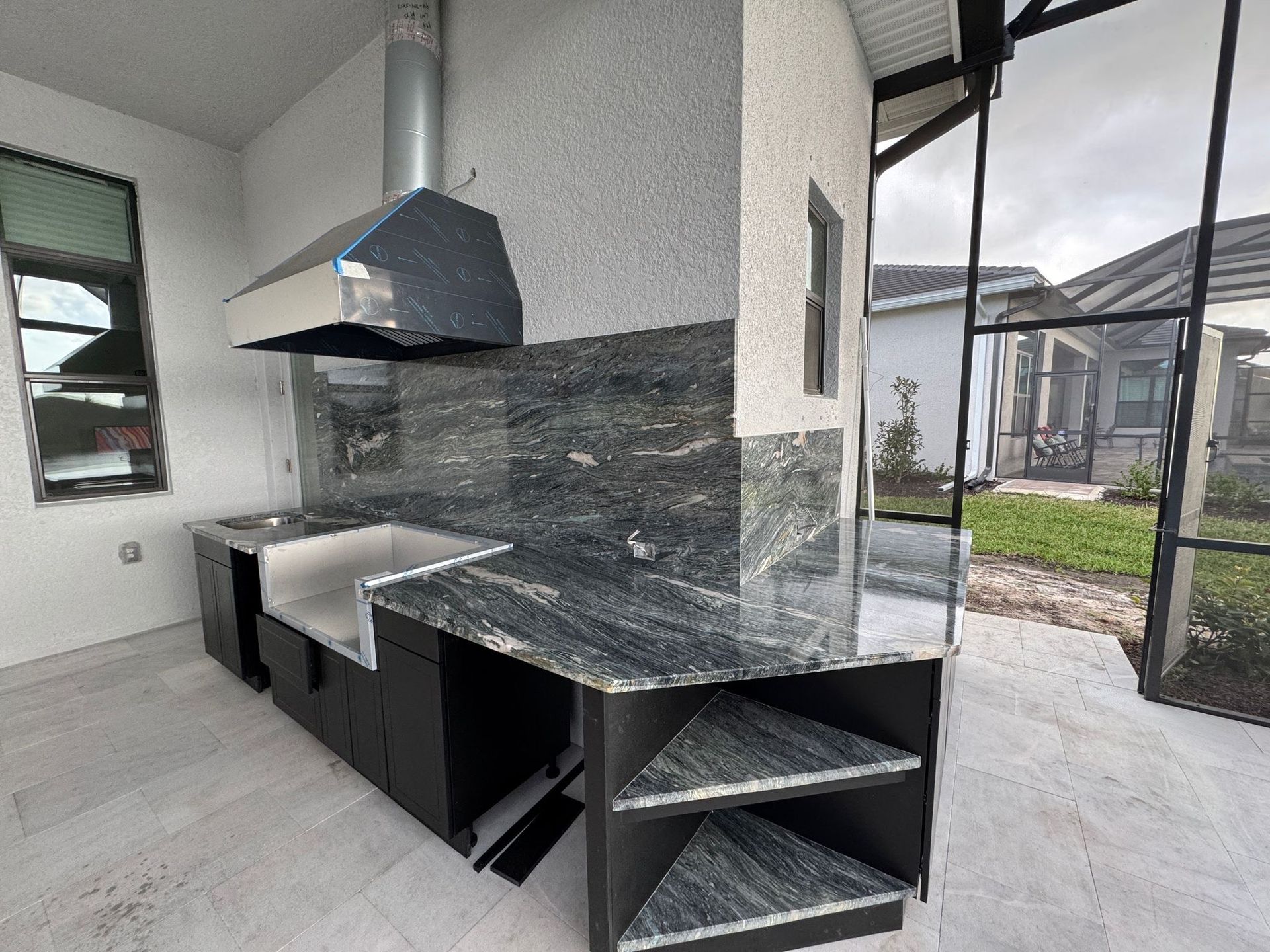 A kitchen with granite counter tops and a stainless steel hood.