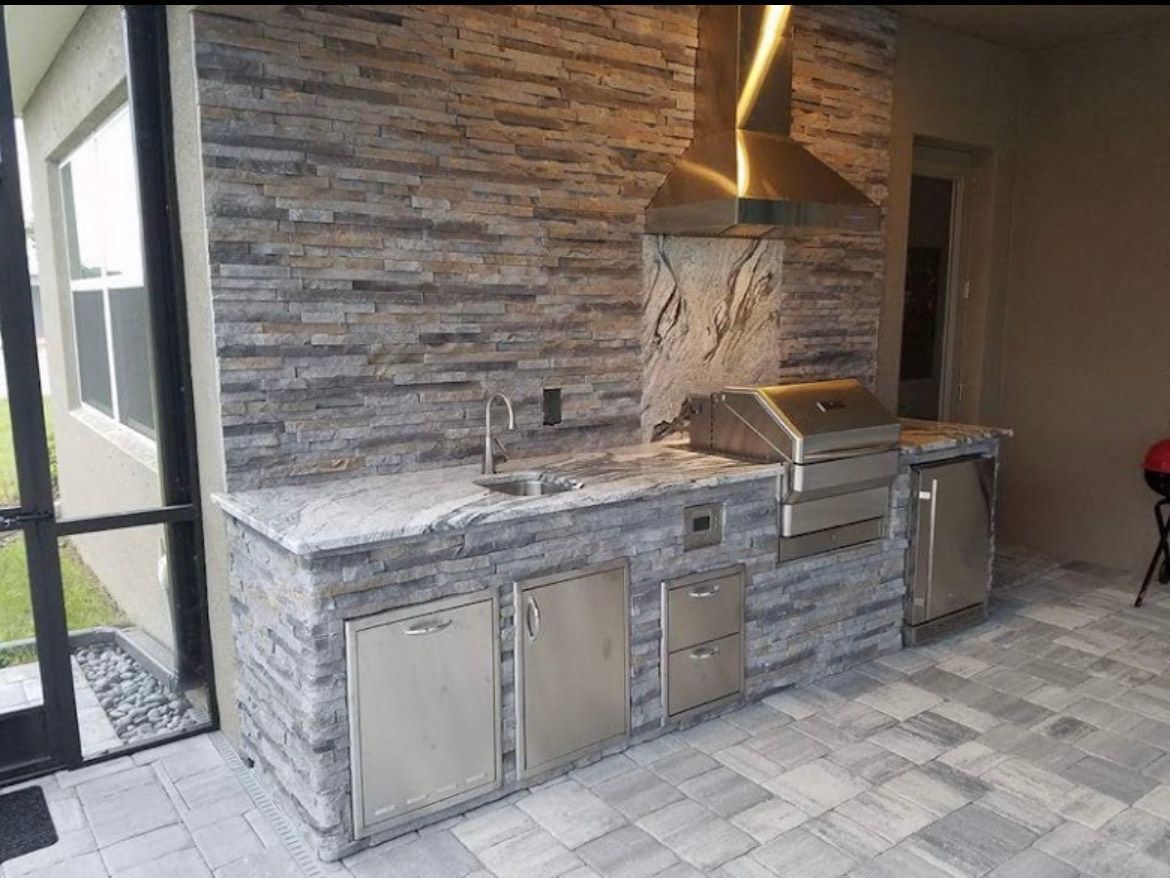 A Kitchen with A Grill , Sink , and Stainless Steel Cabinets.