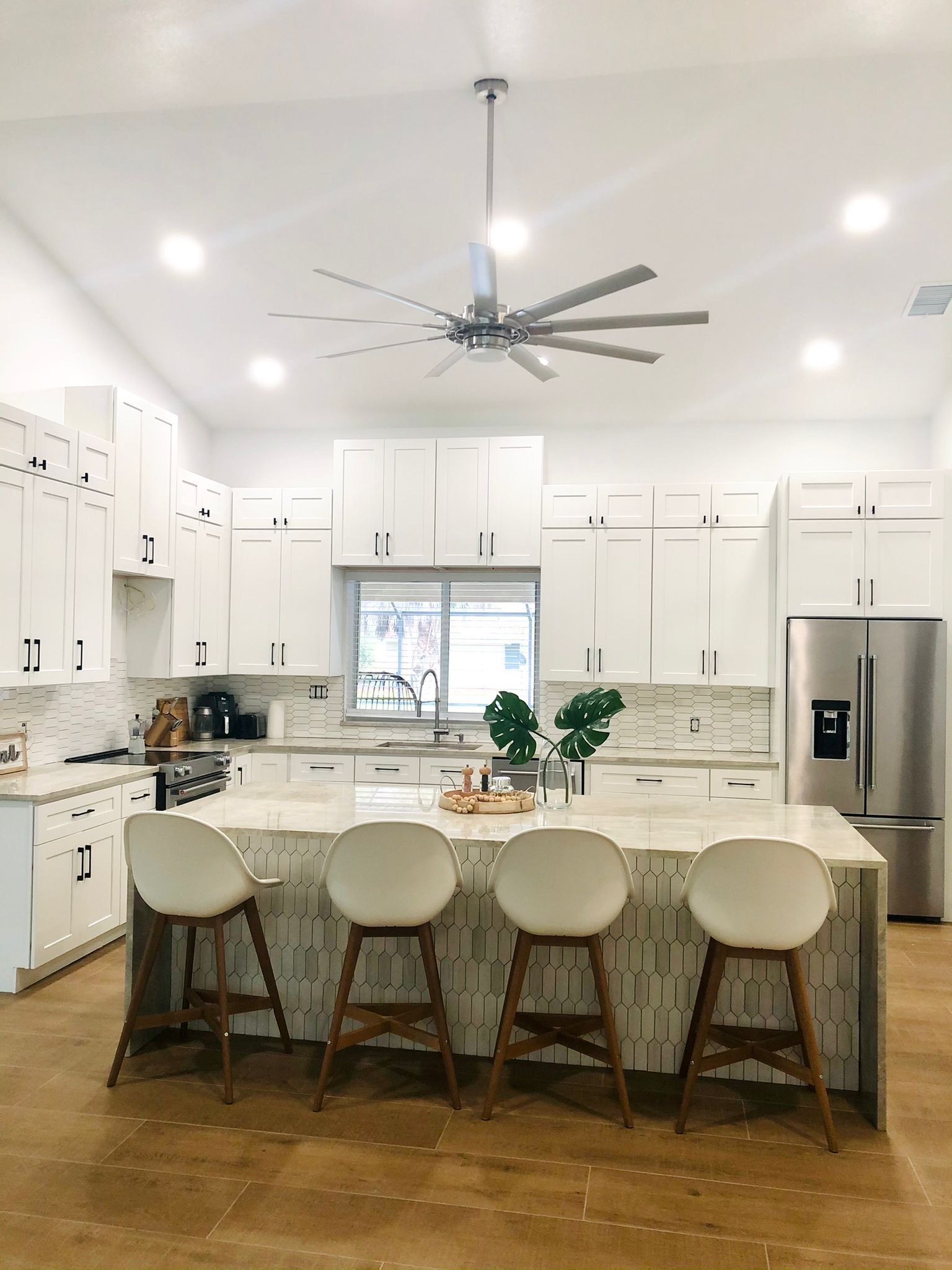 A Kitchen with White Cabinets and Stools and A Ceiling Fan