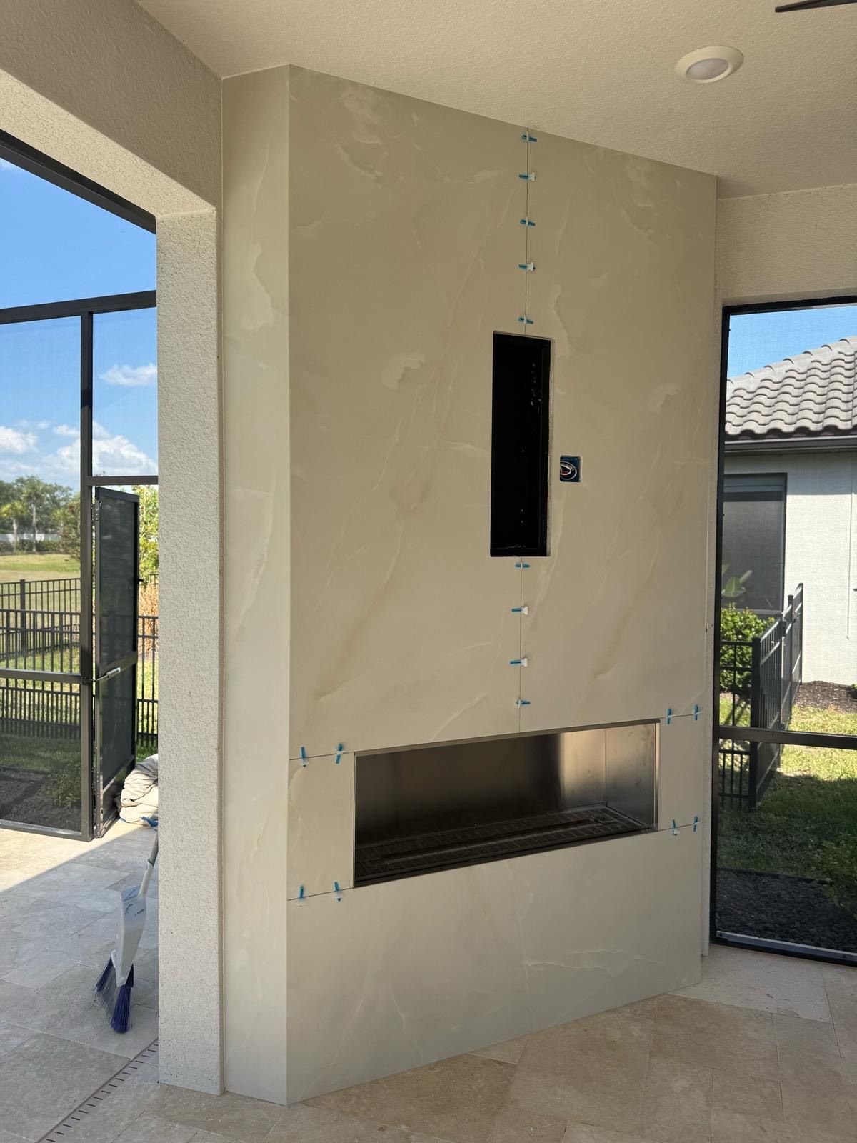 A fireplace is being built in a room with a large window.