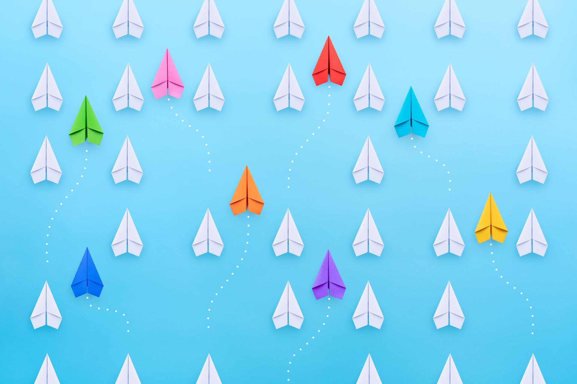 A bunch of paper airplanes are flying in a row on a blue background.