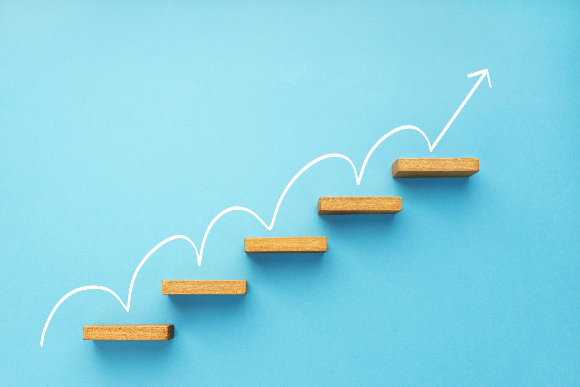 A wooden staircase with an arrow pointing up on a blue background.