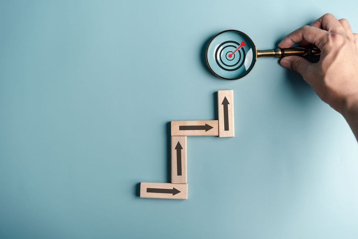 A person is holding a magnifying glass over a target.