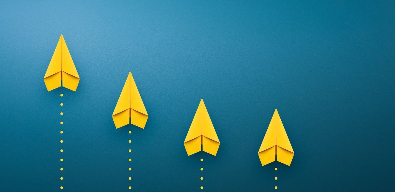 Four yellow paper airplanes are flying in opposite directions on a blue background.