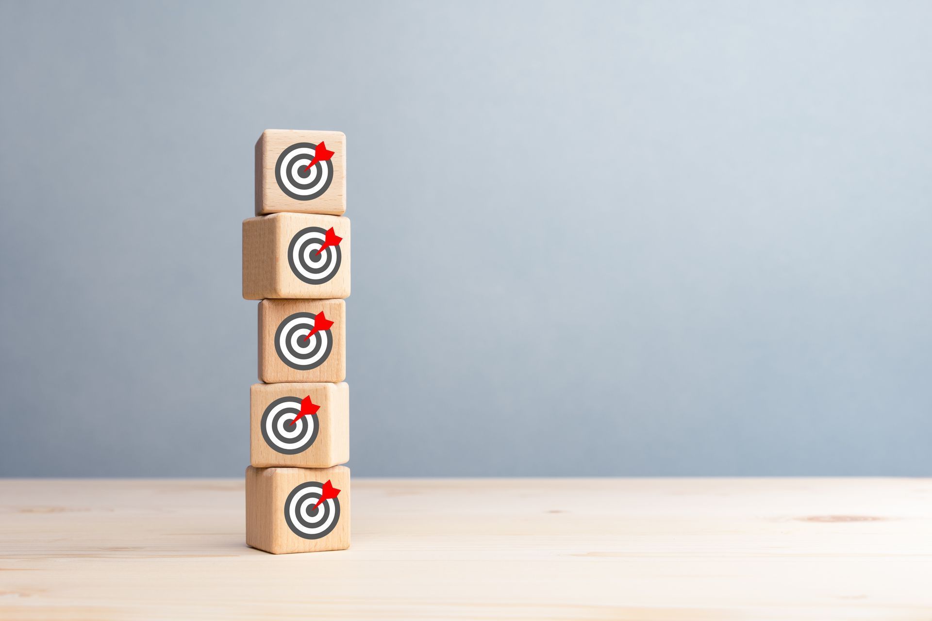 A stack of wooden blocks with darts on them on a wooden table.