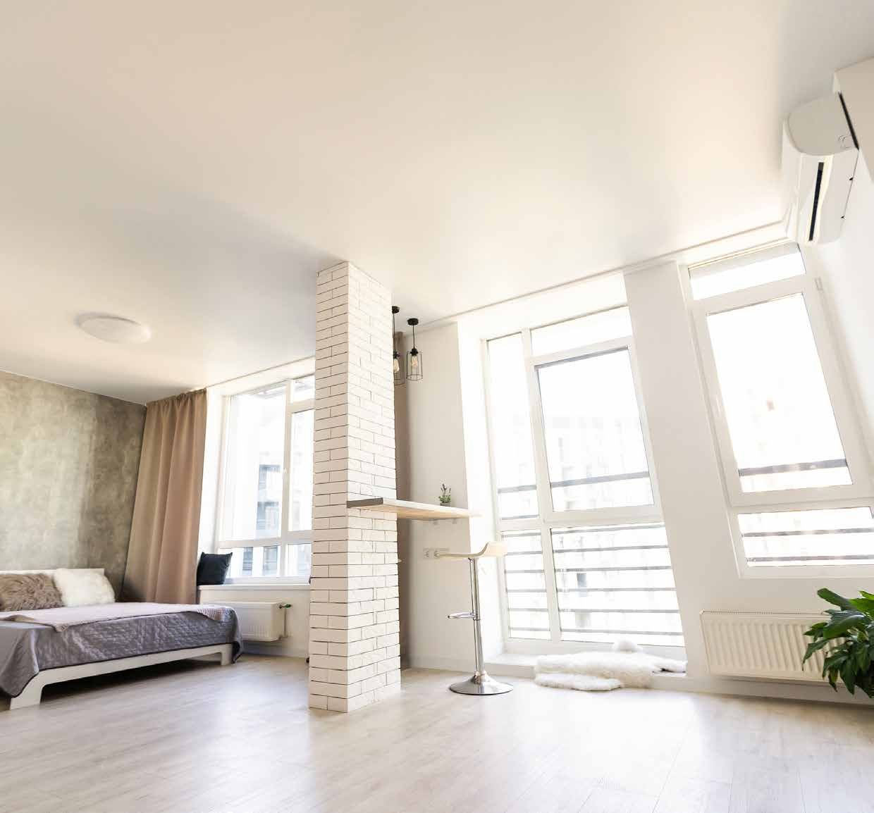 A living room with a bed , couch , and lots of windows.