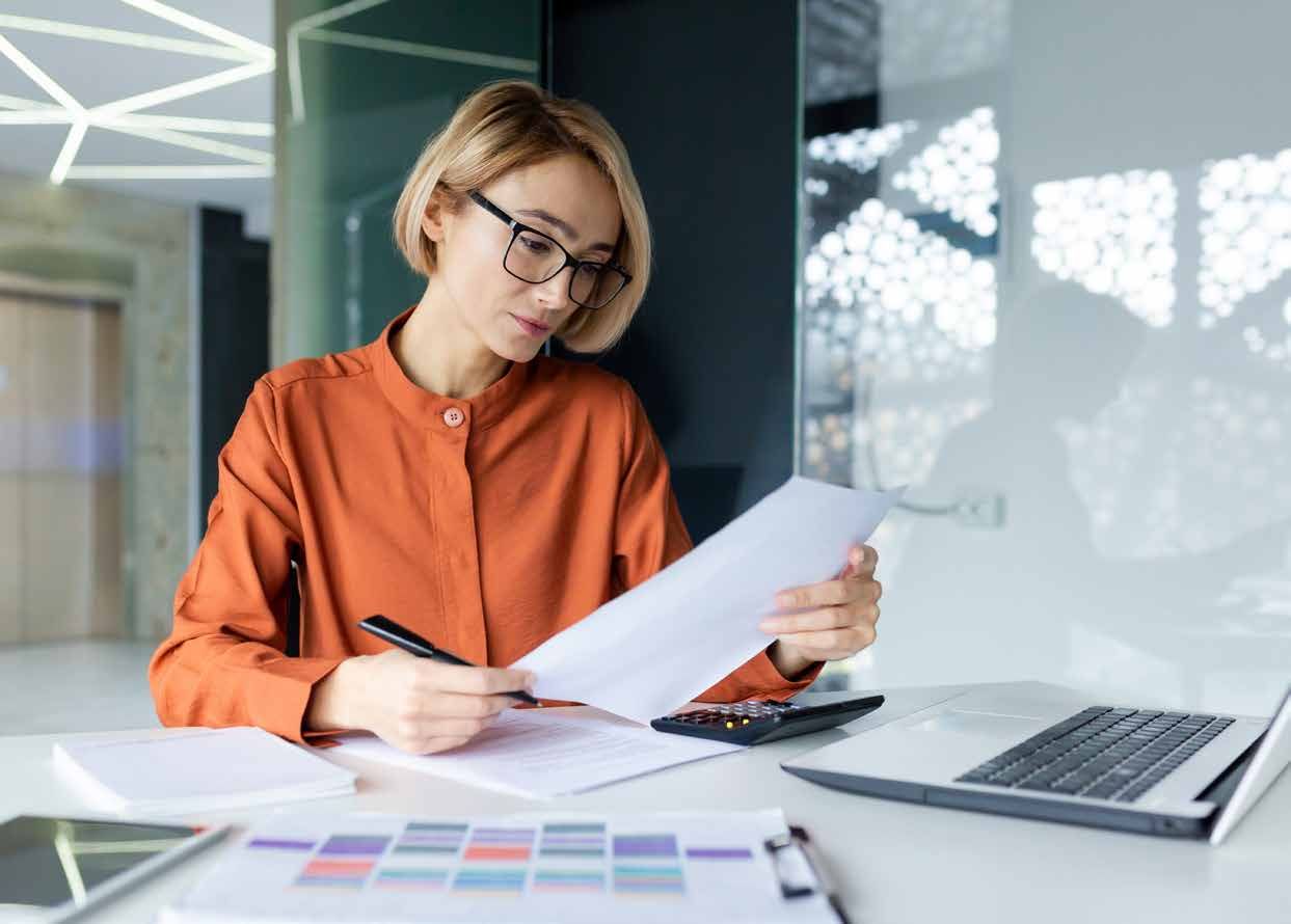A woman is sitting at a desk looking at a piece of paper.