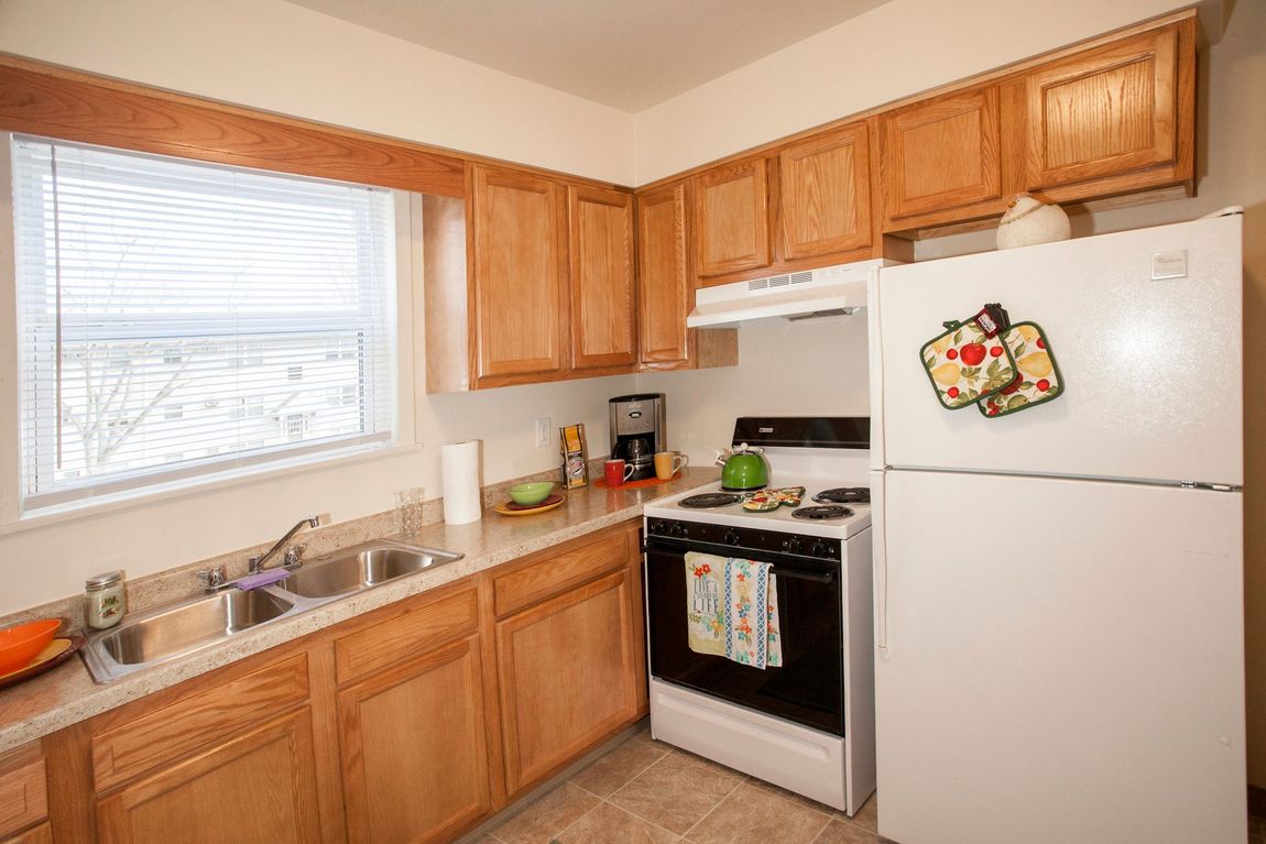Small kitchen with wood cabinets, white appliances, and a window.