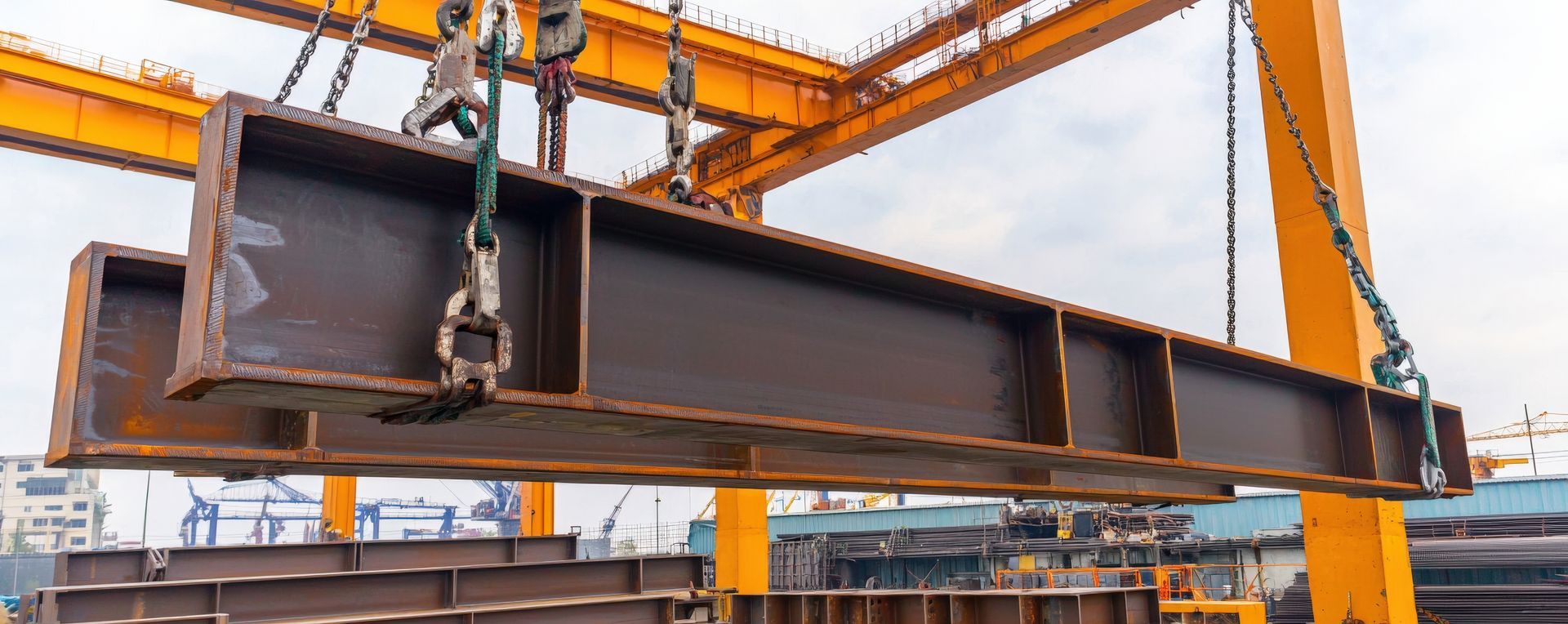 Steel beam being lifted by an orange crane at an industrial site