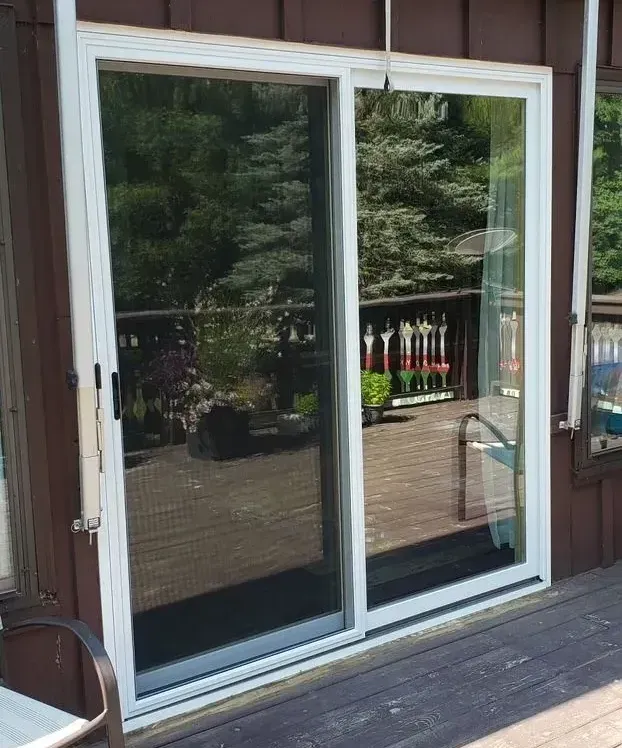 A sliding glass door with a reflection of a deck in it.
