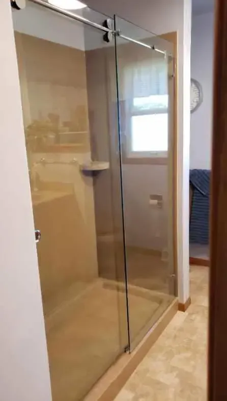 A bathroom with a sliding glass shower door and a window.
