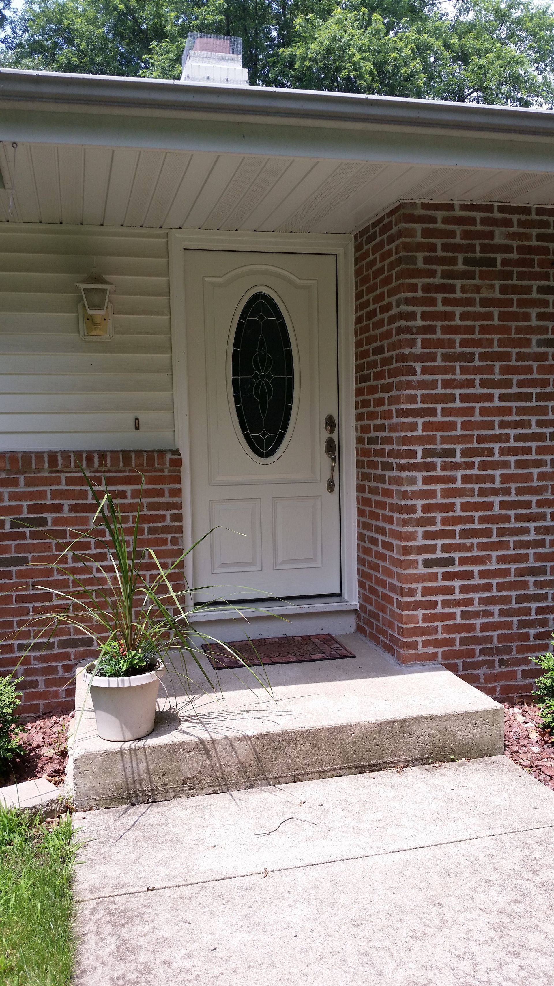 The front door of a brick house with a white door and steps.