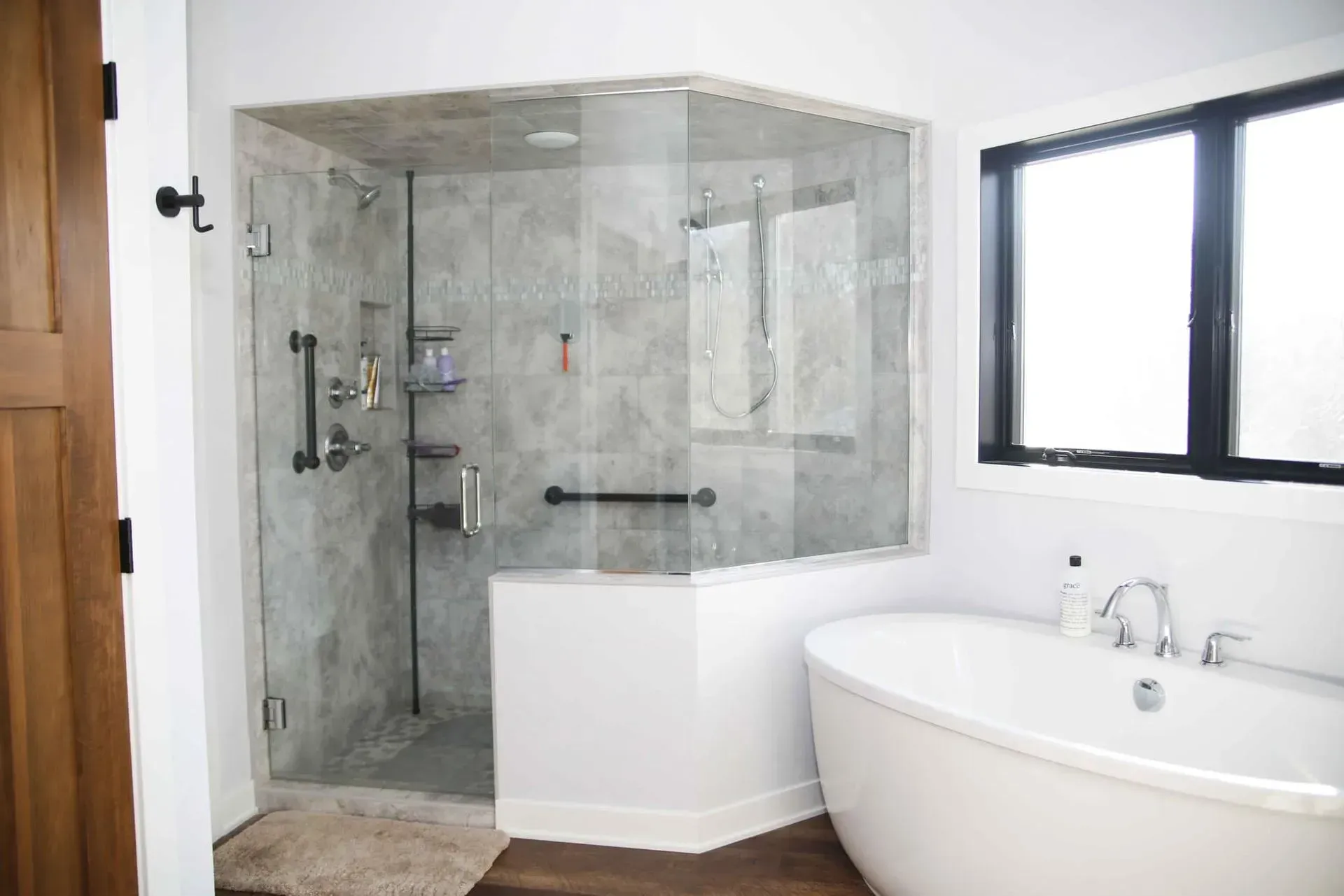 Custom frameless glass shower enclosure with black hardware in a modern Janesville, WI bathroom