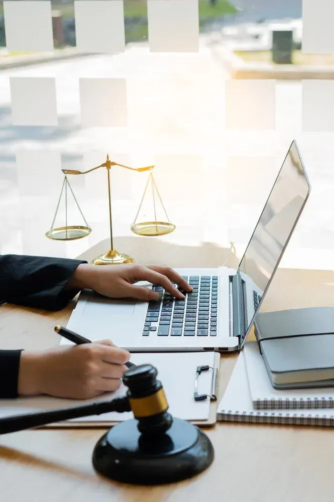Lawyer Typing on Laptop Beside Gavel and Scales of Justice in A Bright Office — David Hunter Solicitor in Lismore, NSW