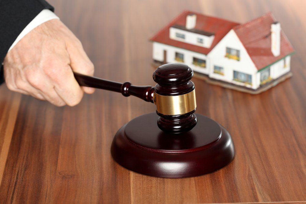 Hand Holding a Gavel Beside a Model House on A Desk — David Hunter Solicitor in Lismore, NSW 2480

