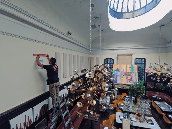 a man on a ladder is measuring a wall with a tape measure