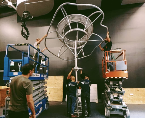 The OTI team using a lift to install a large sculpture
